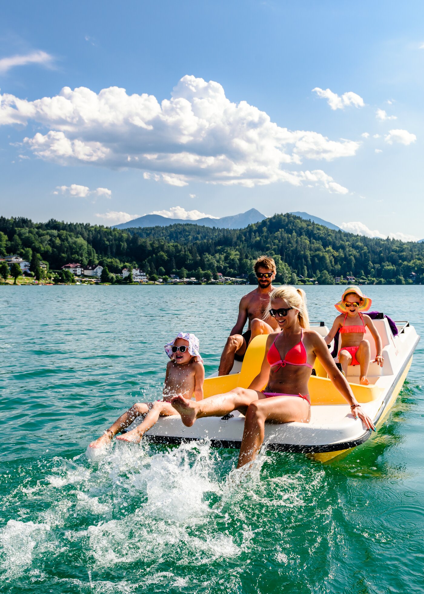 Familie mit Kindern auf einem Tretboot am türkisen Klopeiner See im Sommer