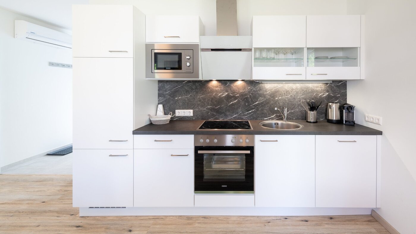 Vollausgestattete Küche mit Backofen, Mikrowelle und Marmor-Rückwand