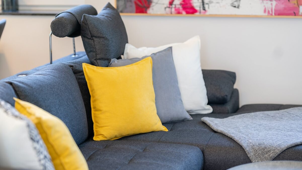 Bequeme Schlafcouch im Wohnzimmer mit gelben Kissen